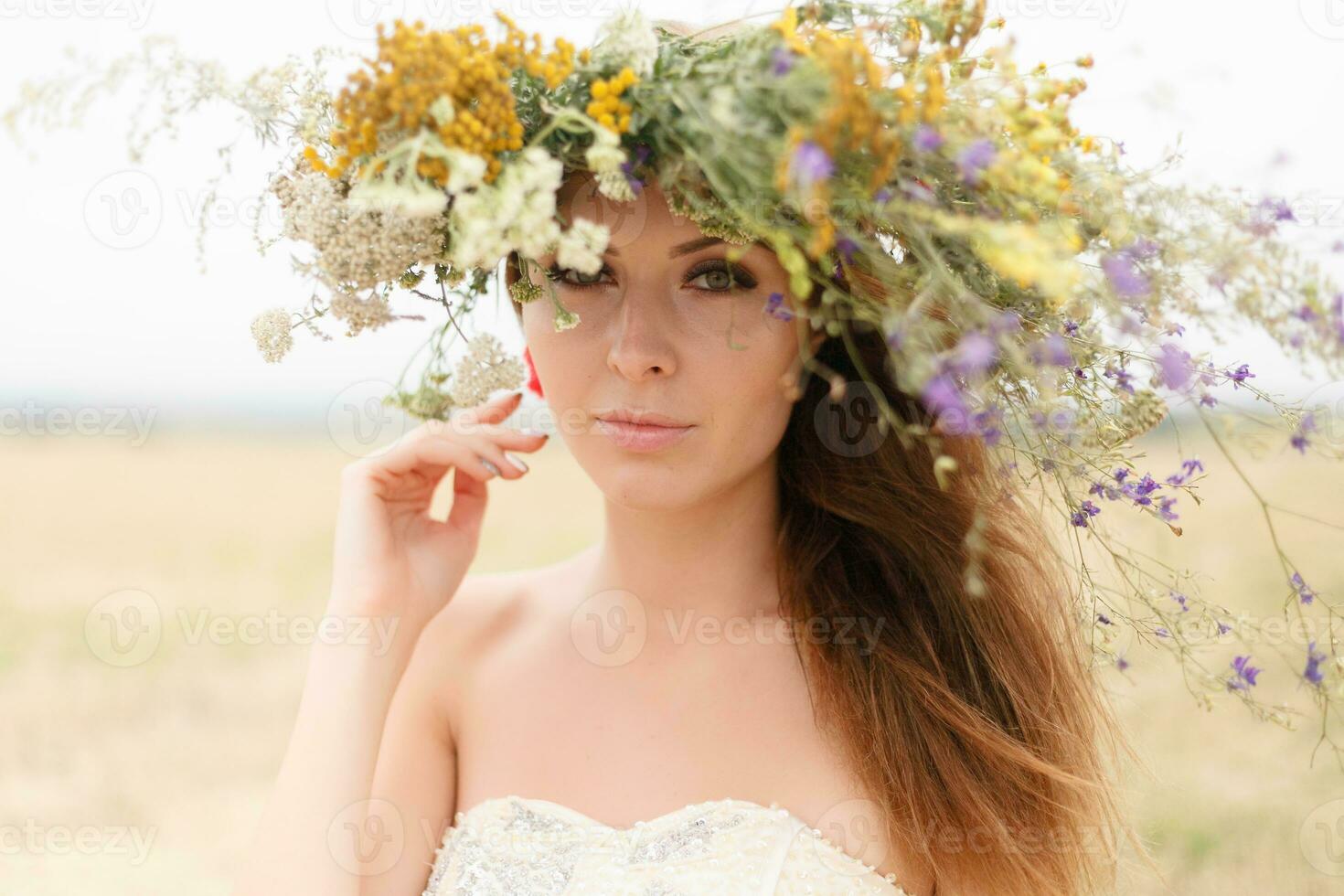 schön Frau mit ein Kranz auf ihr Kopf Sitzung im ein Feld im Blumen foto