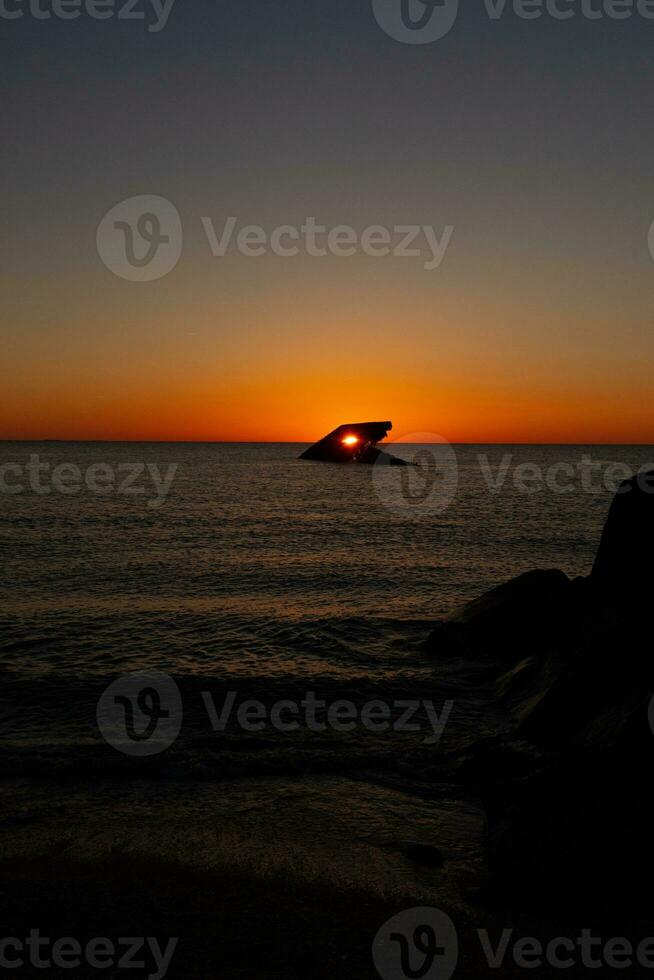 das versunken Schiff von Kap kann Neu Jersey während Sonnenuntergang. das Sonne Beschichtung oben perfekt mit Rumpf zu aussehen mögen ein glühend Auge. das Himmel hat schön Farben von Orange fast mögen es ist auf Feuer. foto