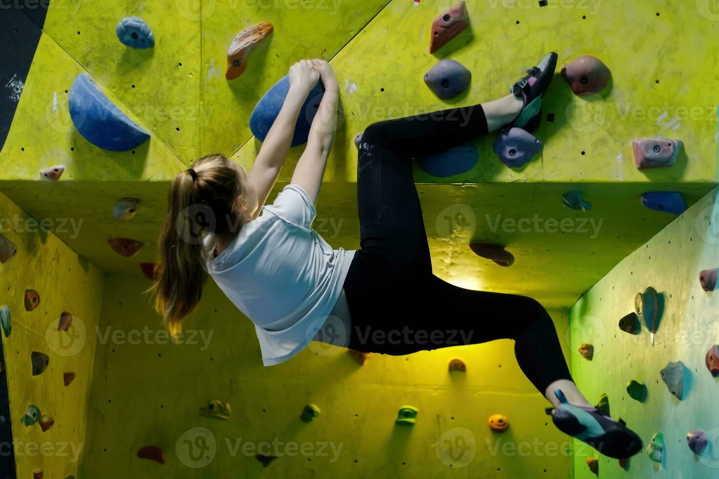 jung Frau Klettern oben auf trainieren Mauer im Fitnessstudio foto