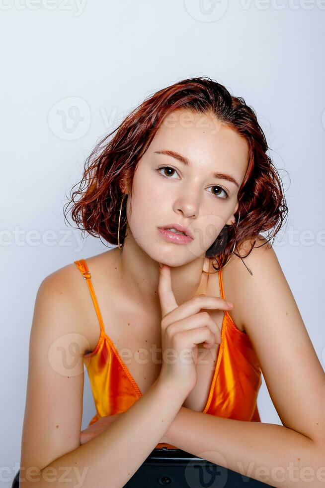 Porträt von attraktiv Mädchen im Orange Kleid im das Studio foto