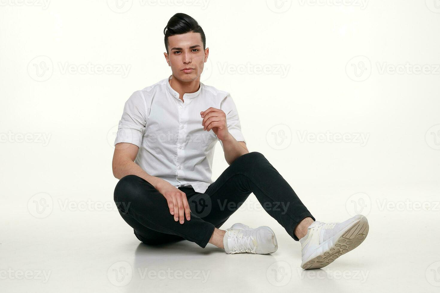 gutaussehend, jung, modisch Mann ist Sitzung auf das Fußboden im Studio foto