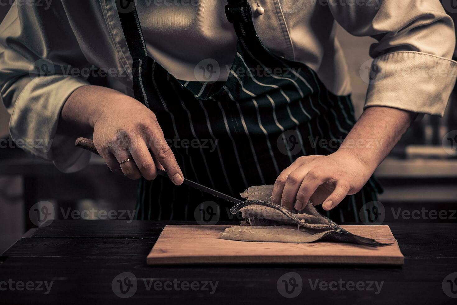 Koch Schneiden das Fisch auf ein Tafel foto