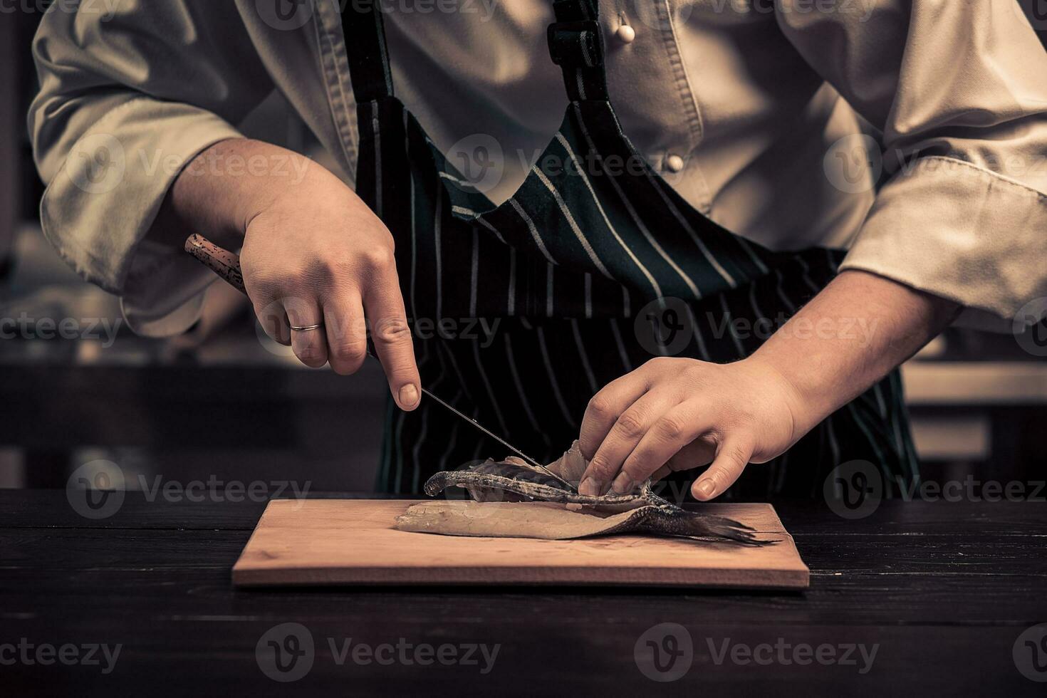 Koch Schneiden das Fisch auf ein Tafel foto