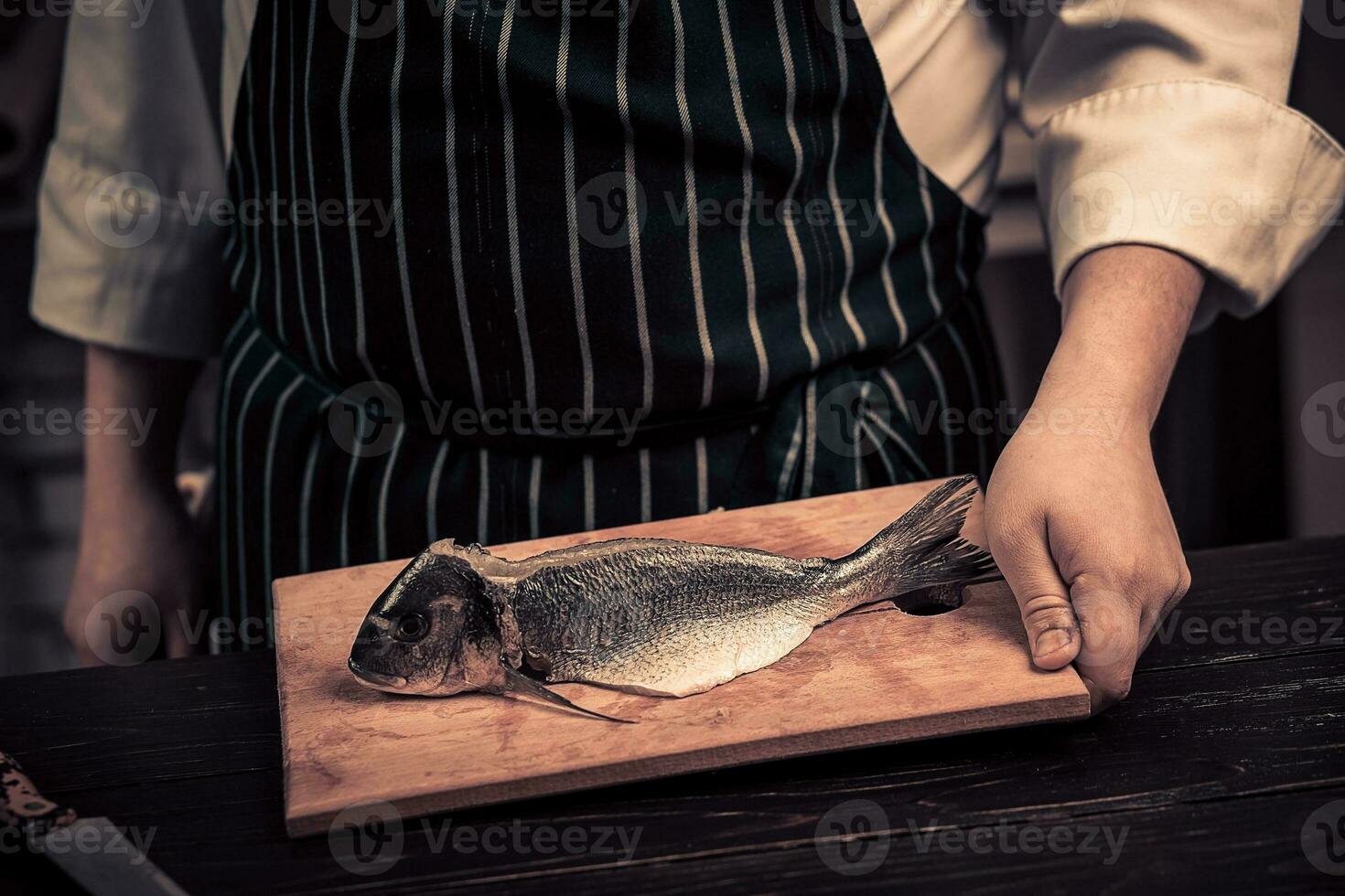 Koch Schneiden das Fisch auf ein Tafel foto