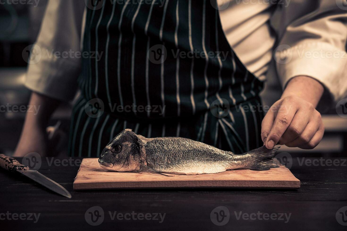 Koch Schneiden das Fisch auf ein Tafel foto