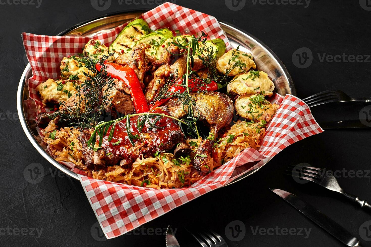 sortiert köstlich gegrillt Fleisch mit Gemüse und Grill Soße auf ein Eisen Tablett auf schwarz Hintergrund schließen hoch. groß einstellen von heiß Fleisch Teller. oben Aussicht foto