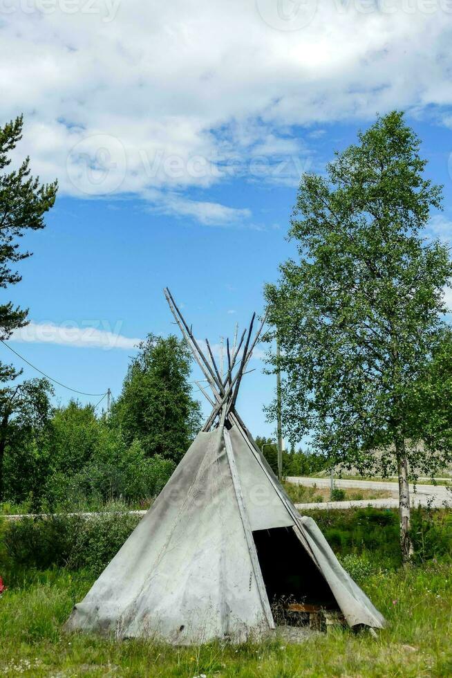 ein Tipi ist Sitzung im das Gras in der Nähe von ein Baum foto