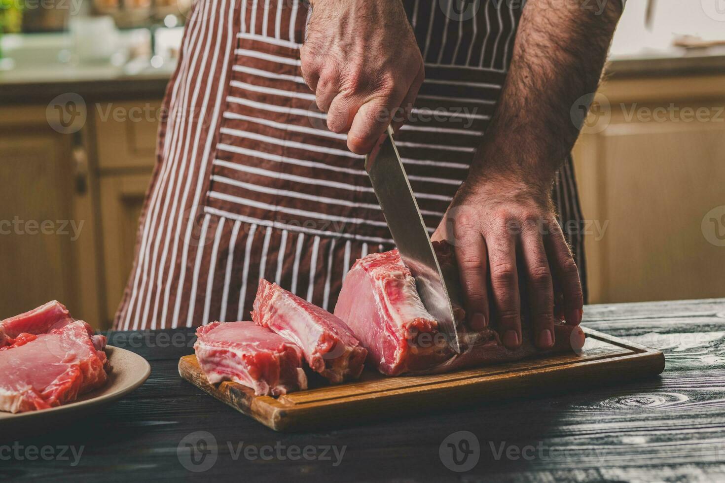 Mann schneidet von frisch Stück von Fleisch auf ein hölzern Schneiden Tafel im das Zuhause Küche foto