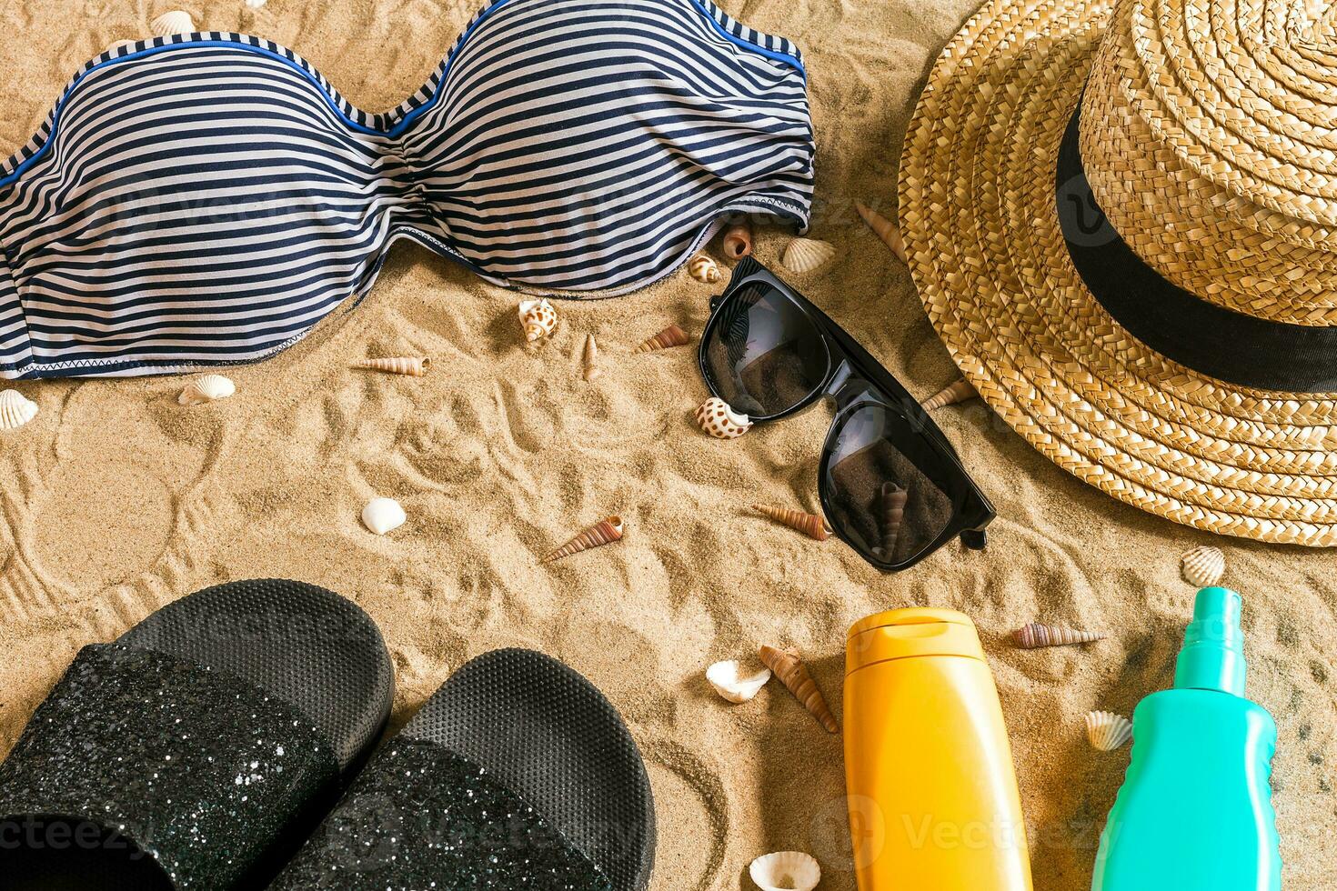 Sommer- Bikini und Zubehör stilvoll Strand Satz, Strand Bikini Sommer- Outfit und Meer Sand wie Hintergrund, oben Sicht, Konzept foto