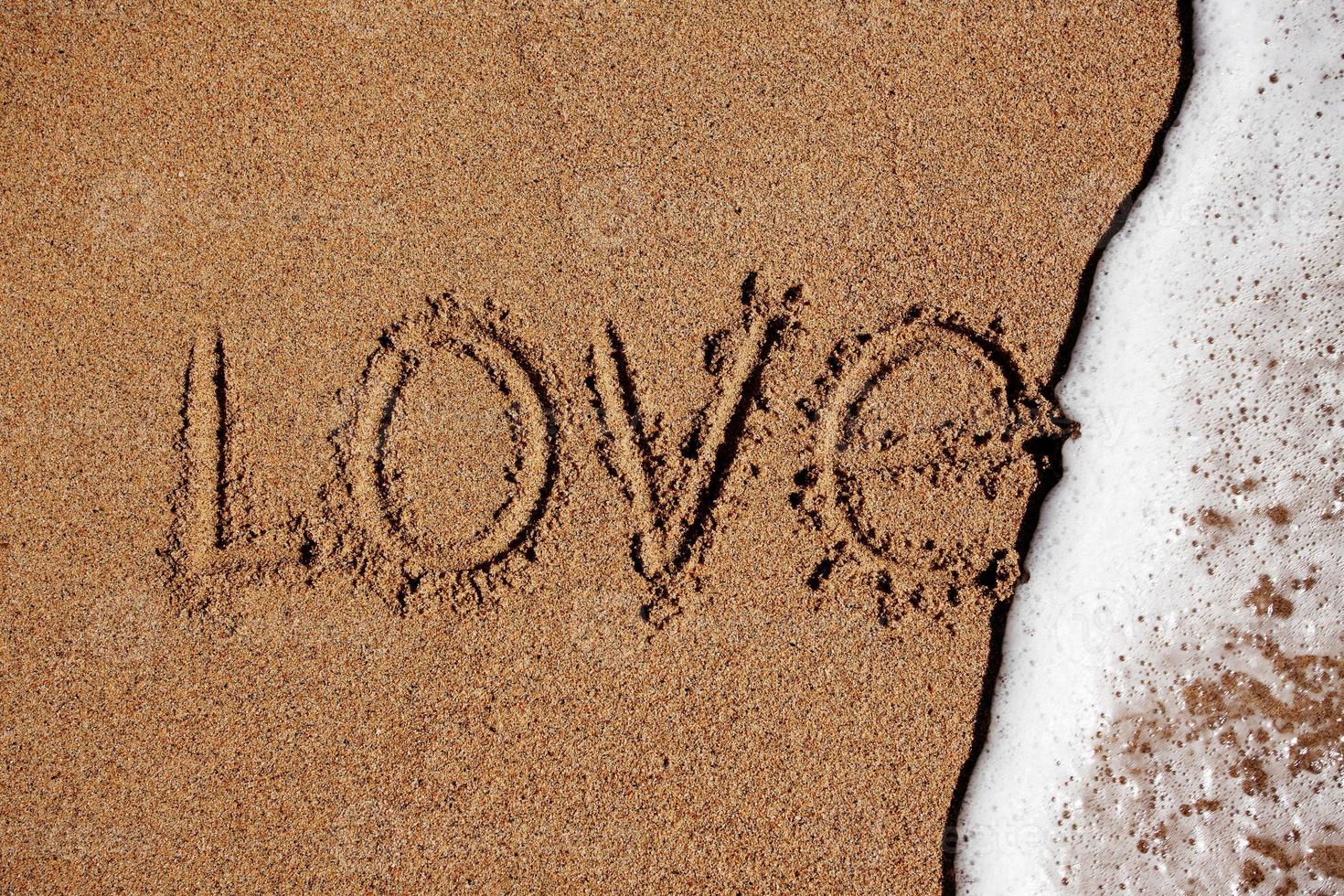 Wort Liebe am Strand wird mit Wasser abgewaschen foto