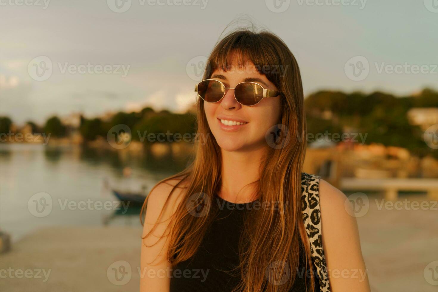 schön Brünette Frau mit stilvoll Frisur Gehen draussen auf das Seebrücke. warm Sunser Farben. Reise und Ferien Konzept. foto