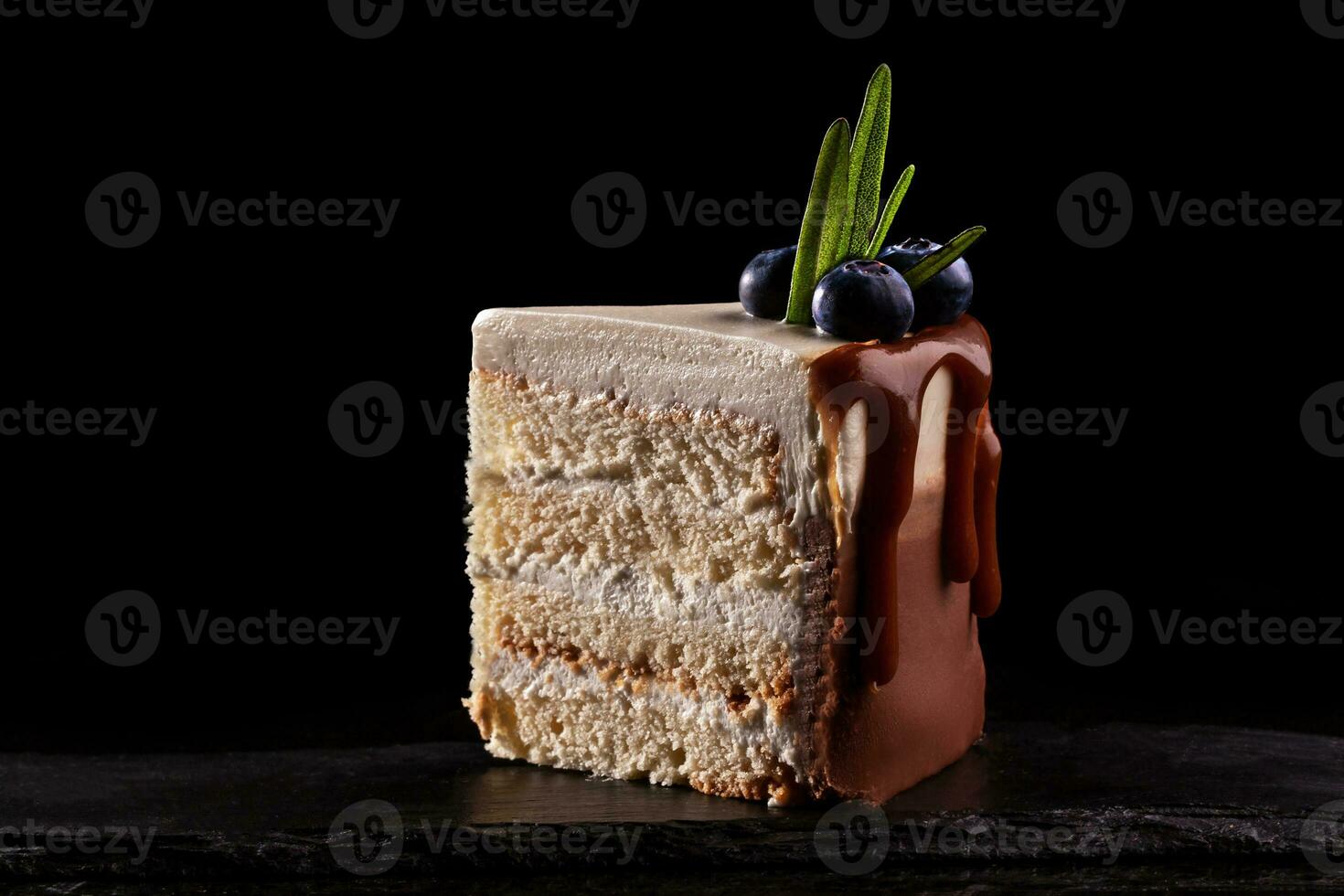 Stück von Kuchen mit Blaubeeren auf ein schwarz Hintergrund, dekoriert mit klein Grün Blätter und frisch Beeren. foto