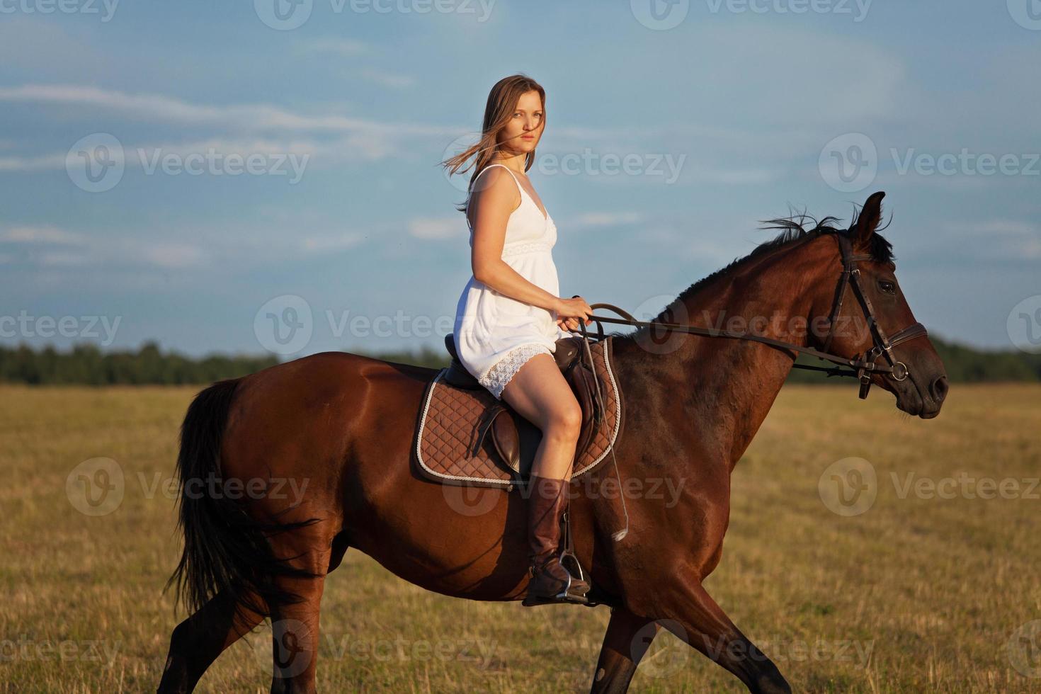 Frau im Kleid reitet auf einem braunen Pferd foto