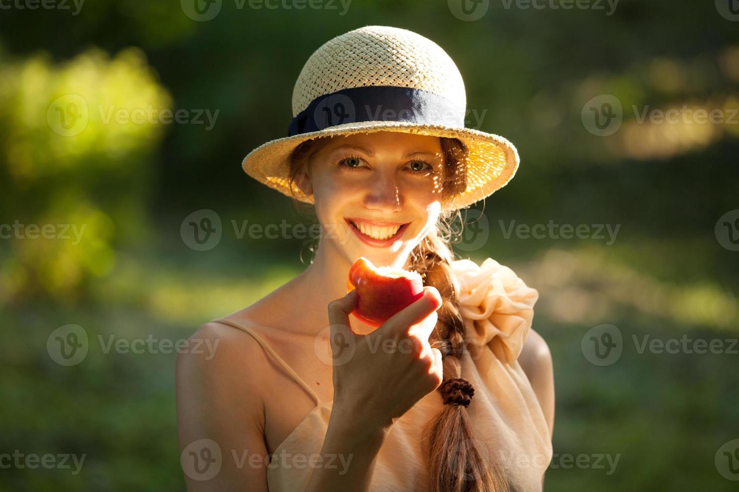 glückliche Frau mit Hut, die Apfel isst foto
