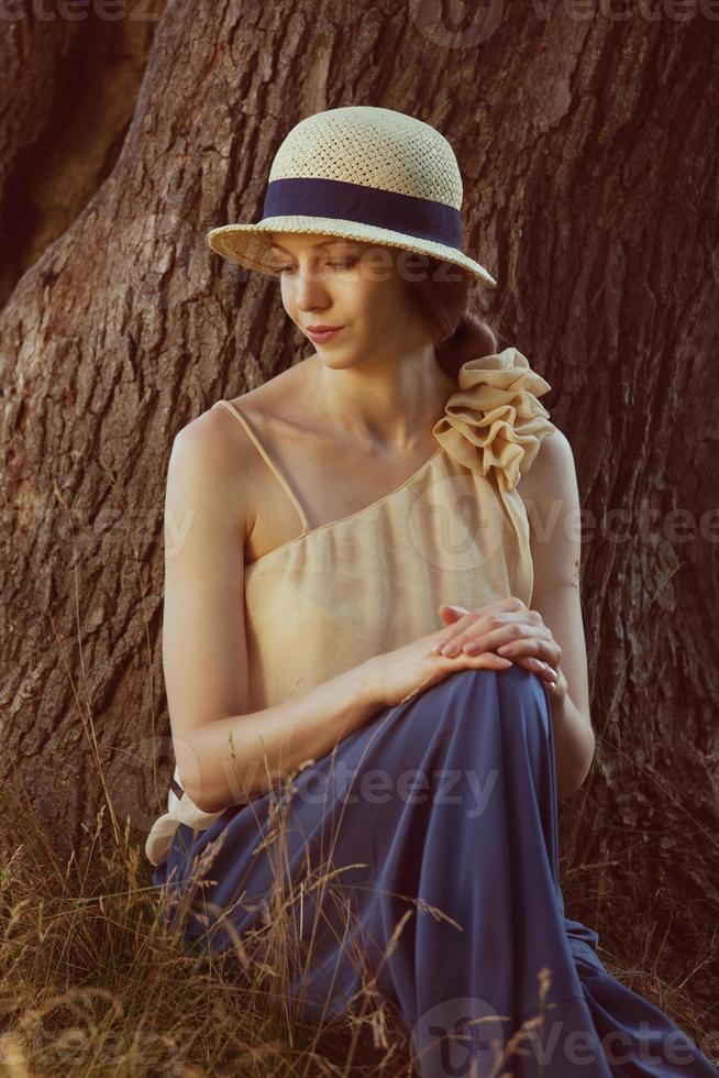junge Frau im Retro-Hut sitzt auf dem Gras foto