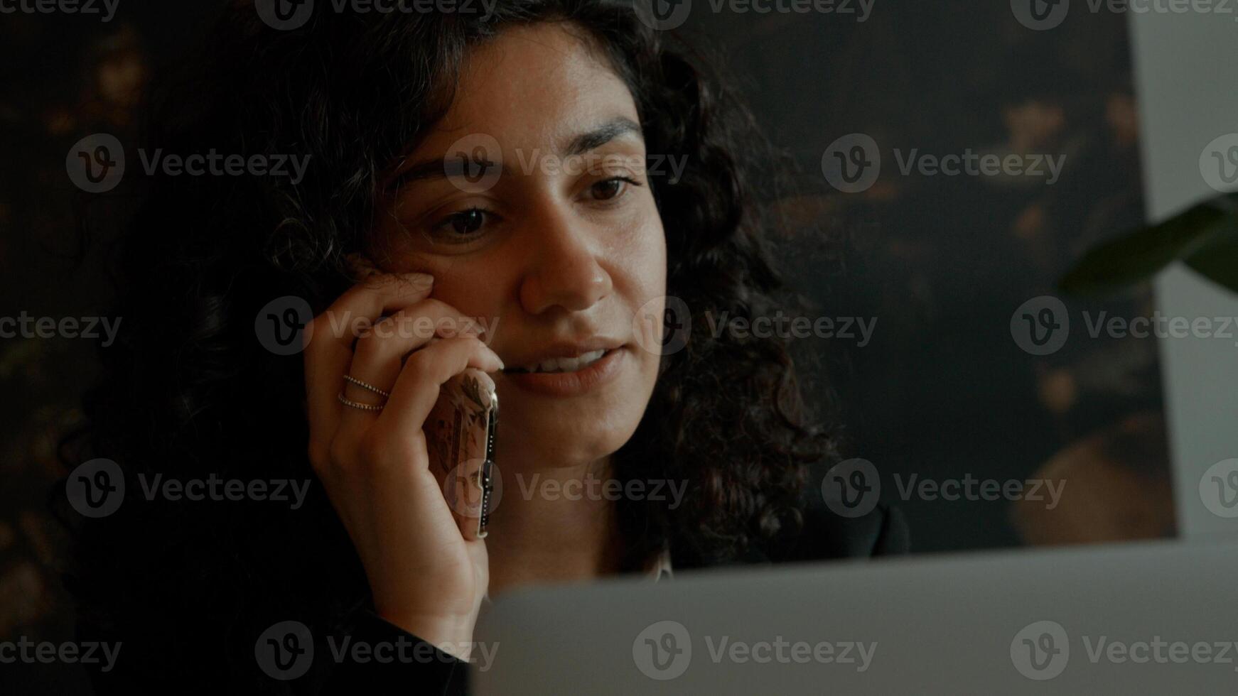 Frau sitzt mit Laptop beim Telefonieren und Trinken foto