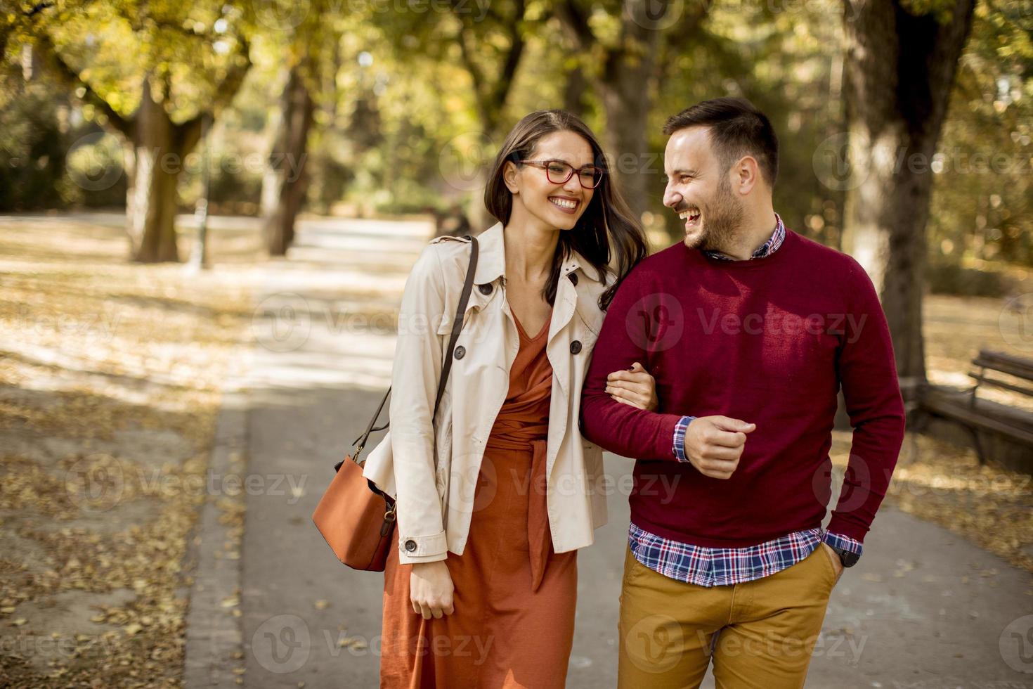 junge Frau und Mann, die Händchen haltend im Stadtpark spazieren gehen foto