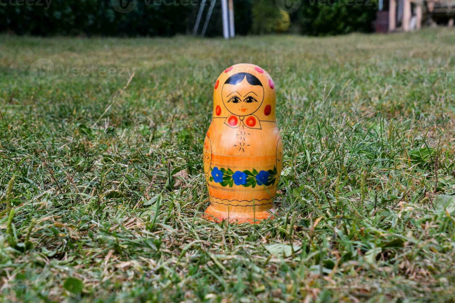 ein klein hölzern Puppe Sitzung im das Gras foto