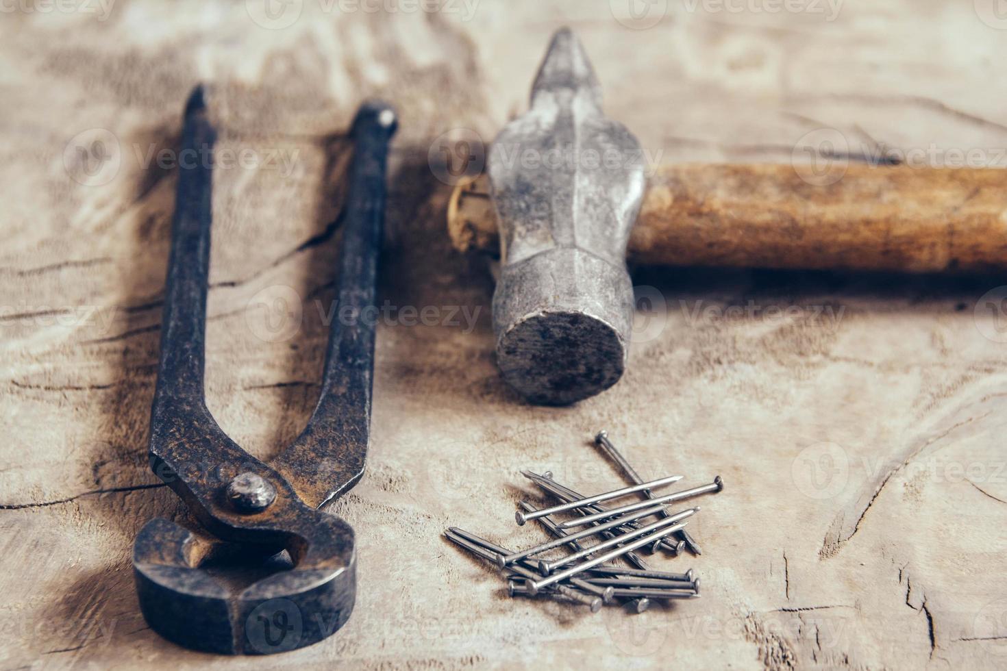 alte rostige Zangen, Nägel und Hammer auf Holzuntergrund foto