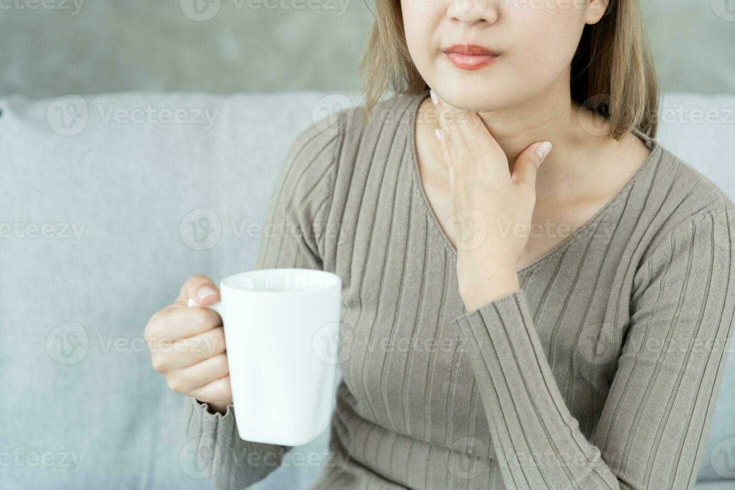 asiatisch Frau stellen ihr Hand auf ihr Hals fällig zu ein wund Kehle. weiblich Mandelentzündung Ursachen ein Entzündung. behandelt durch nehmen Wasser, nehmen Antibiotika, konsultieren ein Arzt, Virus, Corona Virus, Grippe, Grippe foto