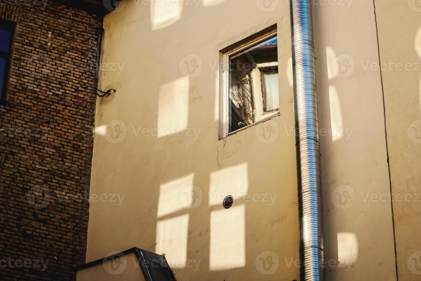 gelbe Betonwand mit offenem Fenster und Glasreflexionen foto