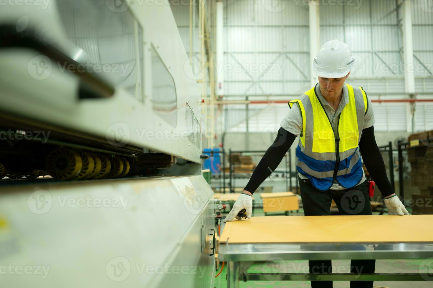 Porträt von ein männlich Arbeiter Arbeiten auf ein Förderer Gürtel im ein Papier Fabrik. Messung und inspizieren das Papier Kommen aus von das Maschine. foto