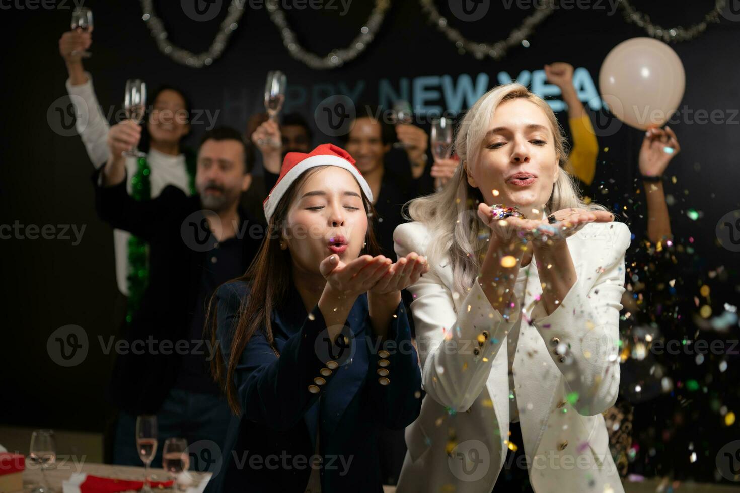 Neu Jahr Party, Gruppe von jung Menschen im Santa Hüte weht Konfetti während feiern Neu Jahr foto