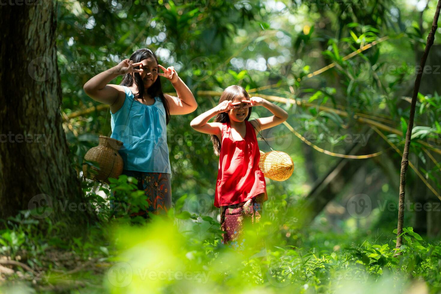 zwei Mädchen asiatisch Frauen mit traditionell Kleidung Stand im das Regenwald. Sie hätten Spaß spielen zusammen Vor assistieren Opa im fangen Fisch im ein in der Nähe See. foto