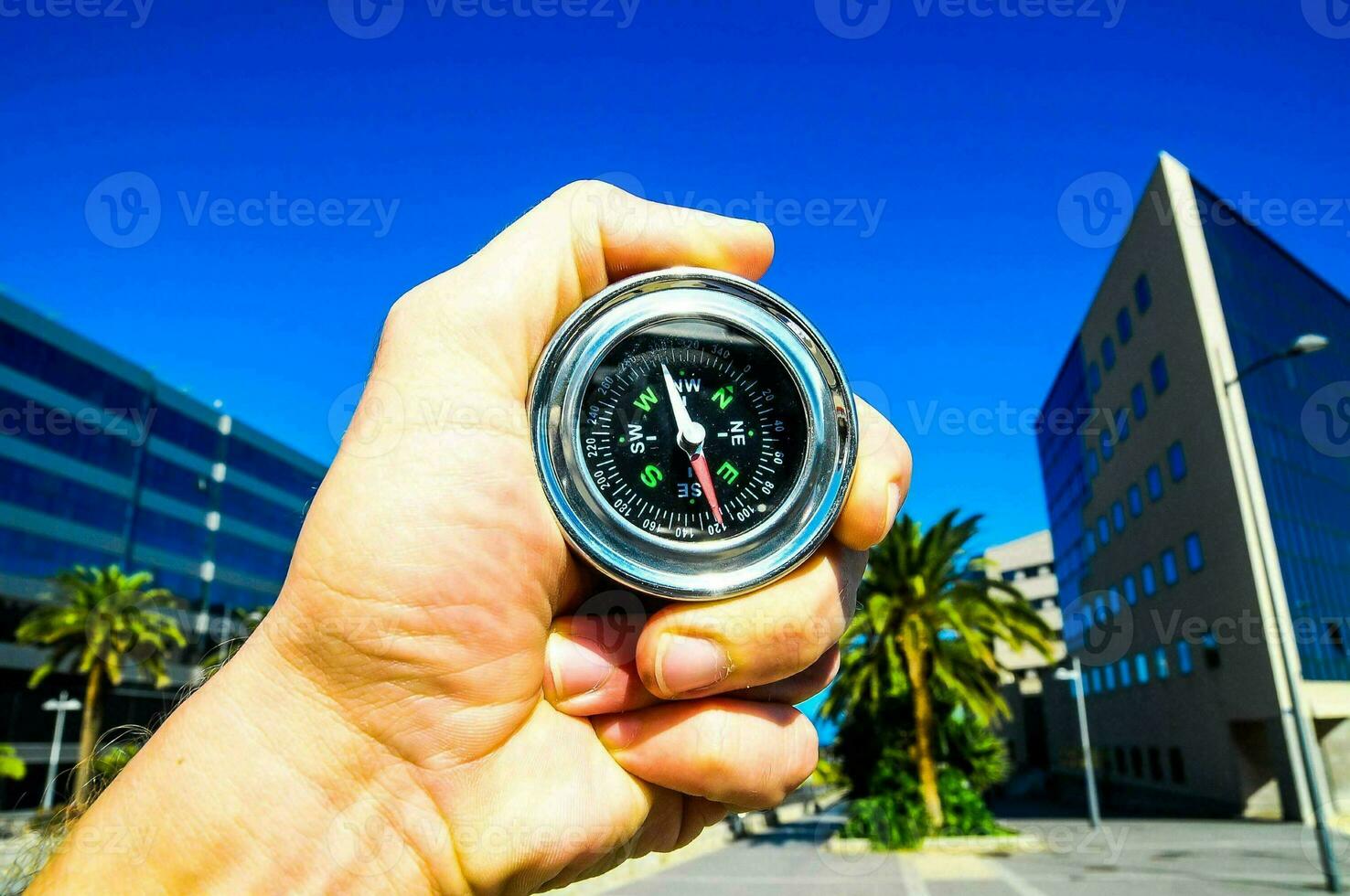 ein Person halten ein Kompass im Vorderseite von ein Gebäude foto