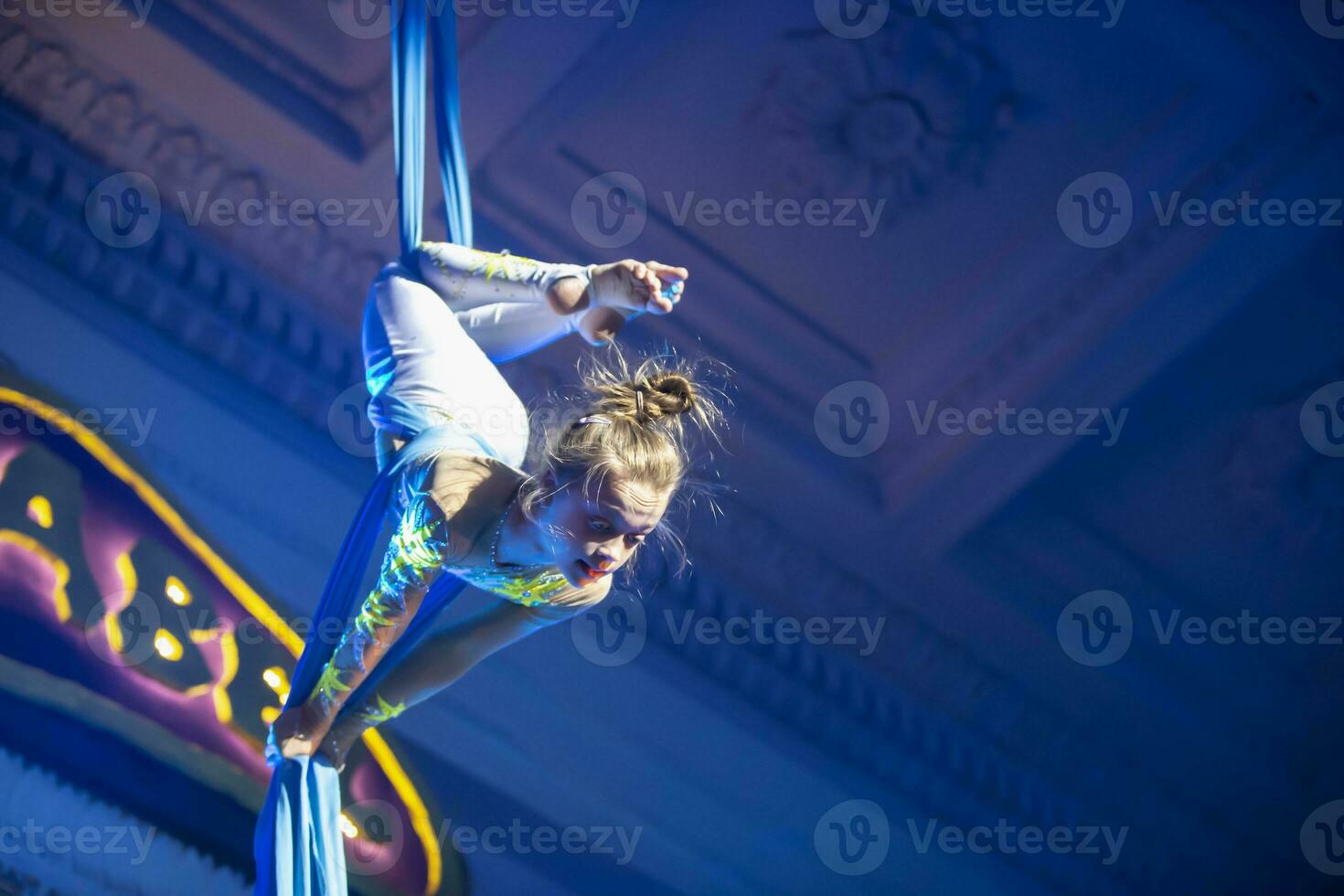 das Mädchen führt aus akrobatisch Zahlen auf das Leinwände. ein klein Zirkus Künstler führt aus auf das Leinwände von Akrobaten. Kind ausführen akrobatisch Elemente im das Luft foto