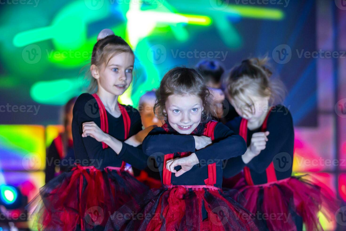 wenig Mädchen sind durchführen ein tanzen Nummer. tanzen zum Hallowinna im rot Anzüge. Mädchen Tanzen. emotional Performance von ein Kinder- tanzen Gruppe. foto