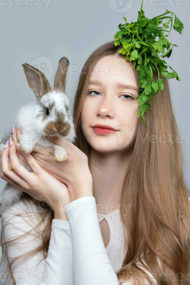 Porträt von ein ländlich Mädchen mit ein Bündel von Petersilie auf ihr Kopf und ein Hase. foto