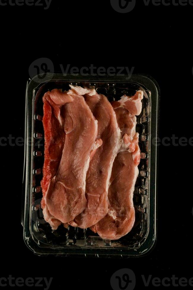 roh Fleisch im ein Plastik Container auf ein schwarz Hintergrund foto