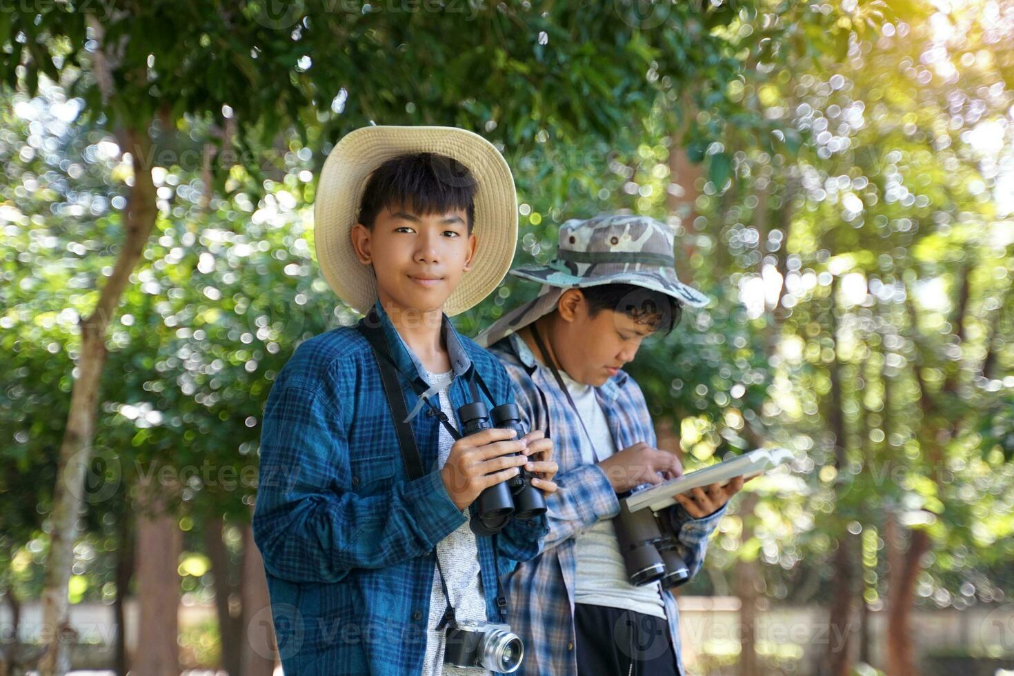 asiatische Jungen verwenden ein Fernglas, um Vögel in einem eigenen Gemeinschaftswald zu beobachten. das Konzept des Lernens aus Lernquellen außerhalb der Schule. Konzentrieren Sie sich auf das erste Kind. foto