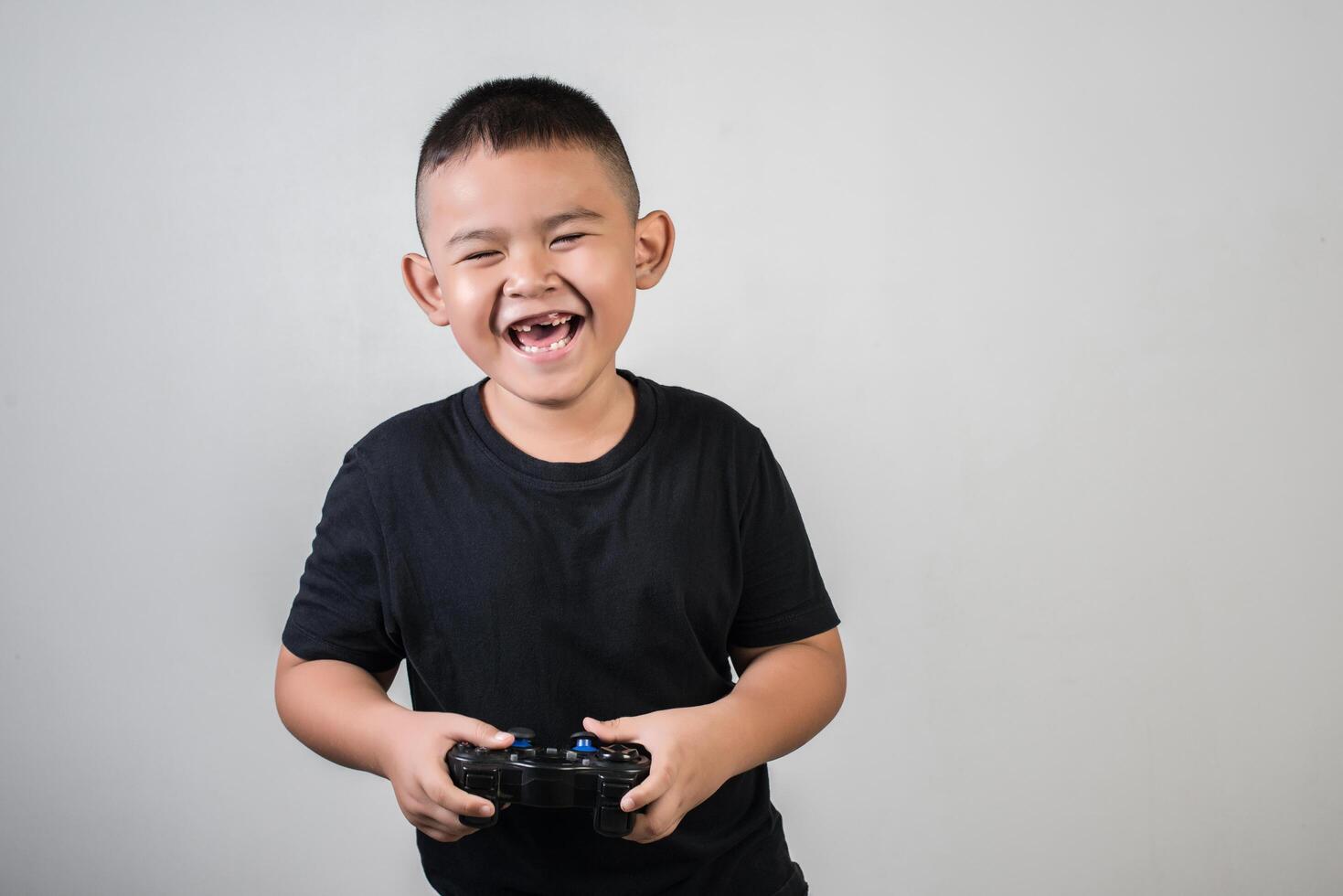 glücklicher Junge spielt Spielcomputer mit einem Controller im Studiofoto foto