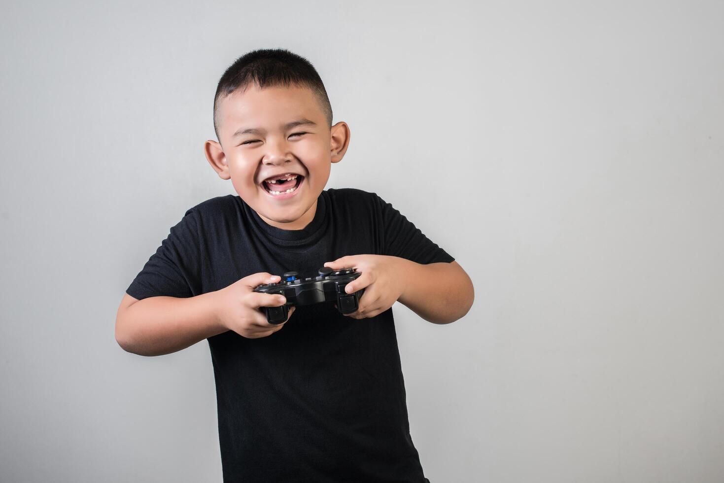 glücklicher Junge spielt Spielcomputer mit einem Controller im Studiofoto foto