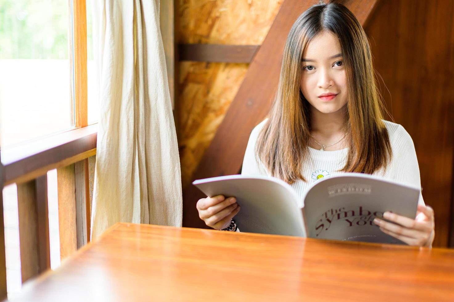schöne Frau sitzt in einem Café und liest ein Buch foto