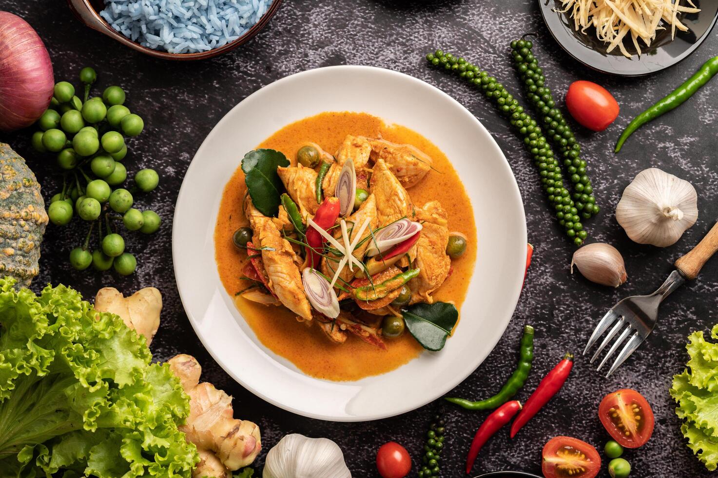 trockenes grünes Curry mit Hühnchen in weißen Tellern auf schwarzem Zement foto