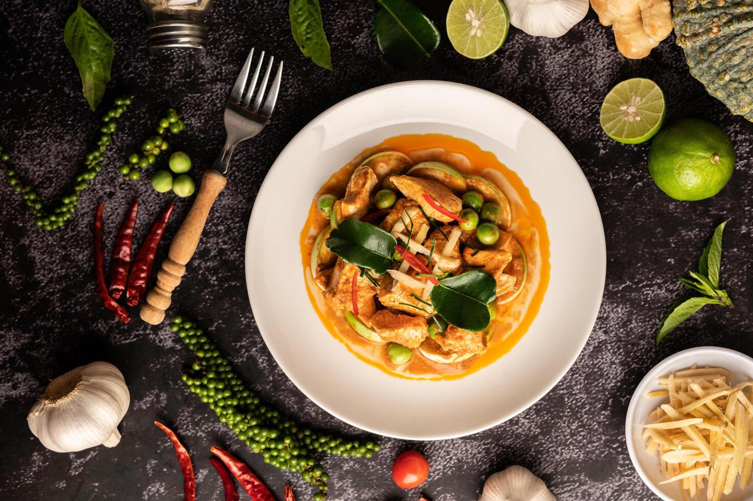 trockenes grünes Curry mit Hühnchen in weißen Tellern auf schwarzem Zement foto