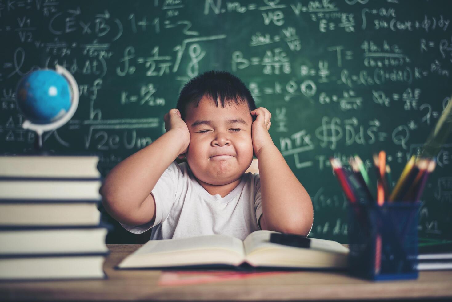 besorgter Junge im Klassenzimmer mit den Händen auf dem Kopf foto