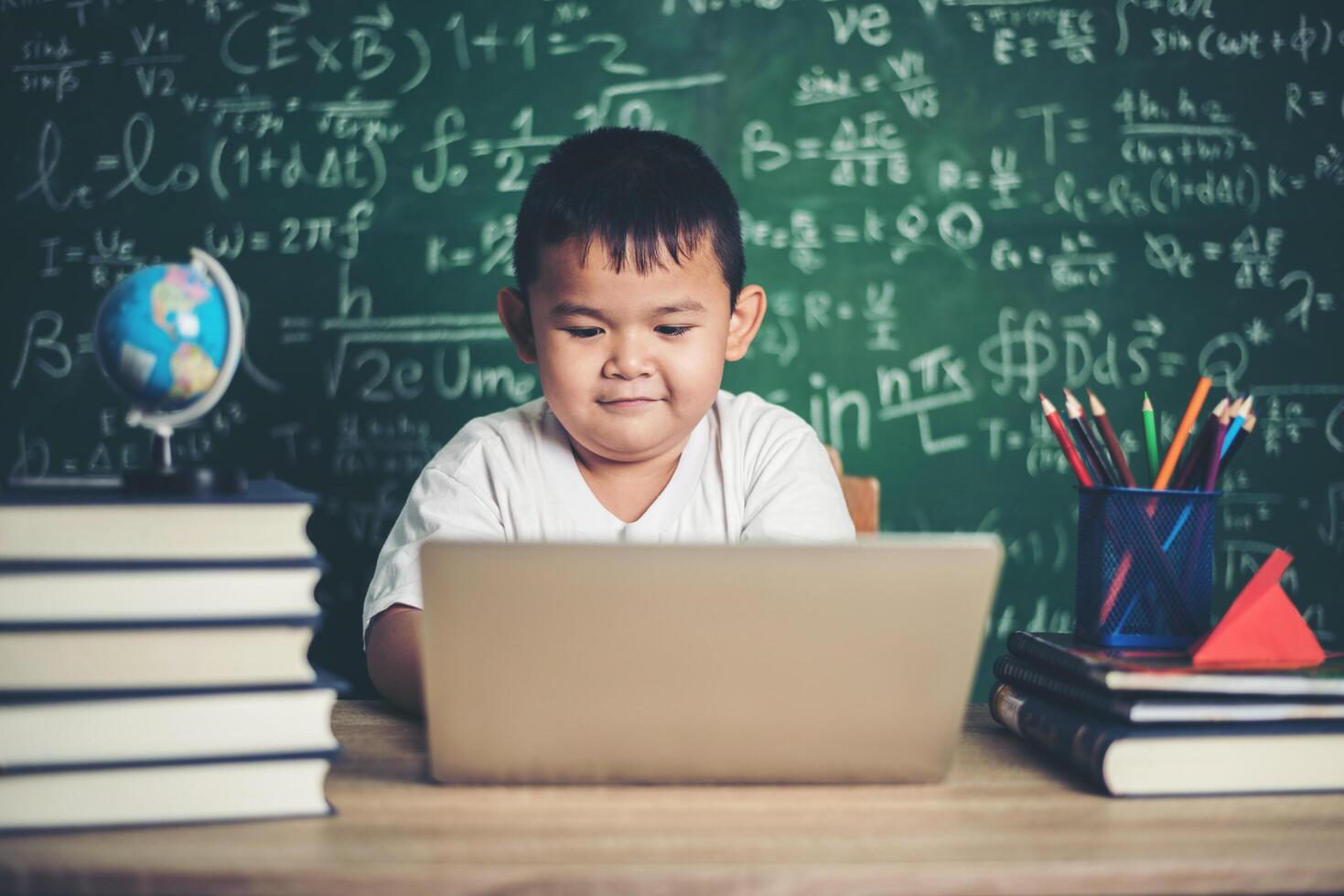 Kind benutzt Computer-Laptop im Klassenzimmer. foto