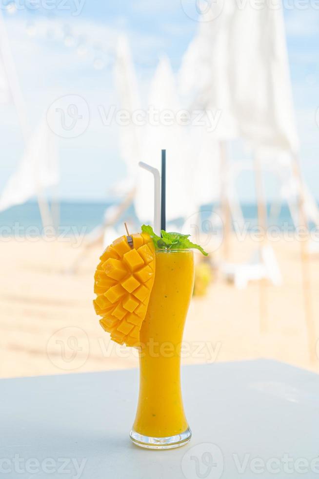 Mango-Smoothies mit Meeresstrand-Hintergrund foto