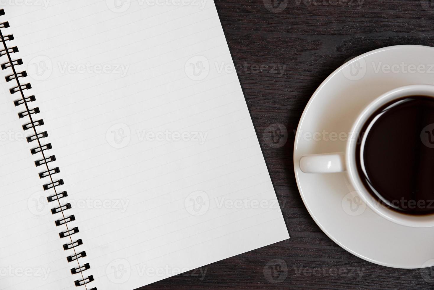 Draufsicht auf Kaffeetasse und leeres Notizbuch für Memo auf Holzboden foto