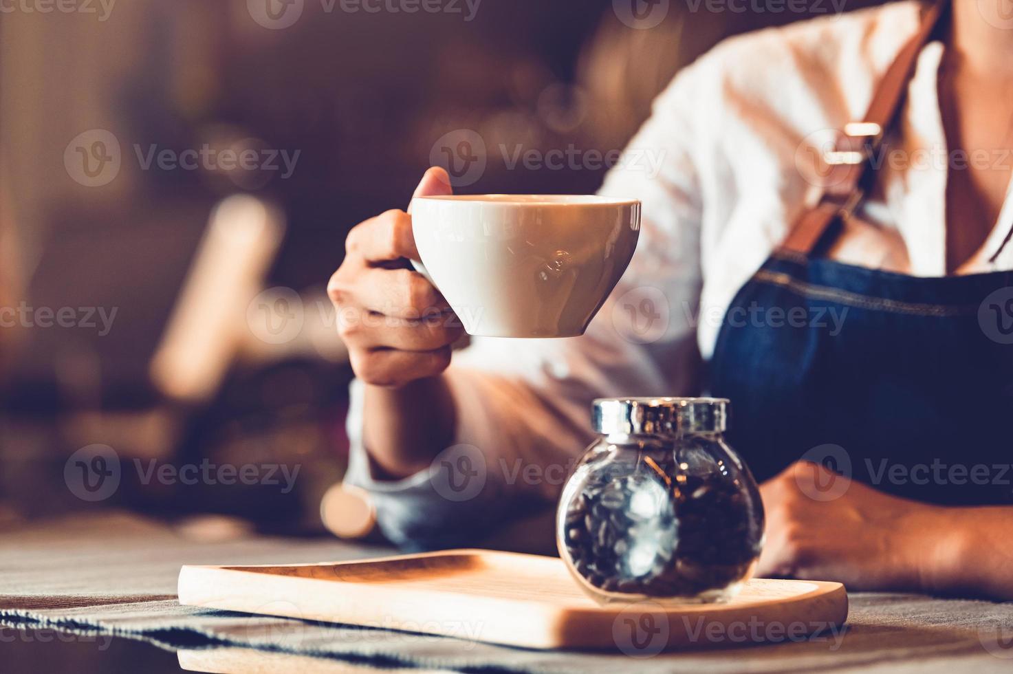 Nahaufnahme der weiblichen Barista-Hand, die Tasse Kaffee macht und hält? foto