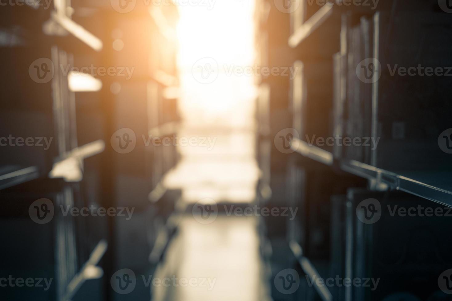 verschwommener Hintergrund der dunklen Bibliothek mit Sonnenschein foto