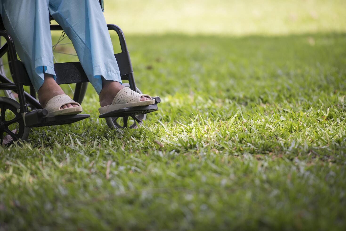 Nahaufnahme einer einsamen älteren Frau, die im Rollstuhl im Garten sitzt foto