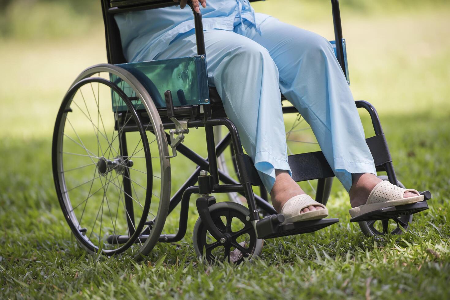 Nahaufnahme einer einsamen älteren Frau, die im Rollstuhl im Garten sitzt foto