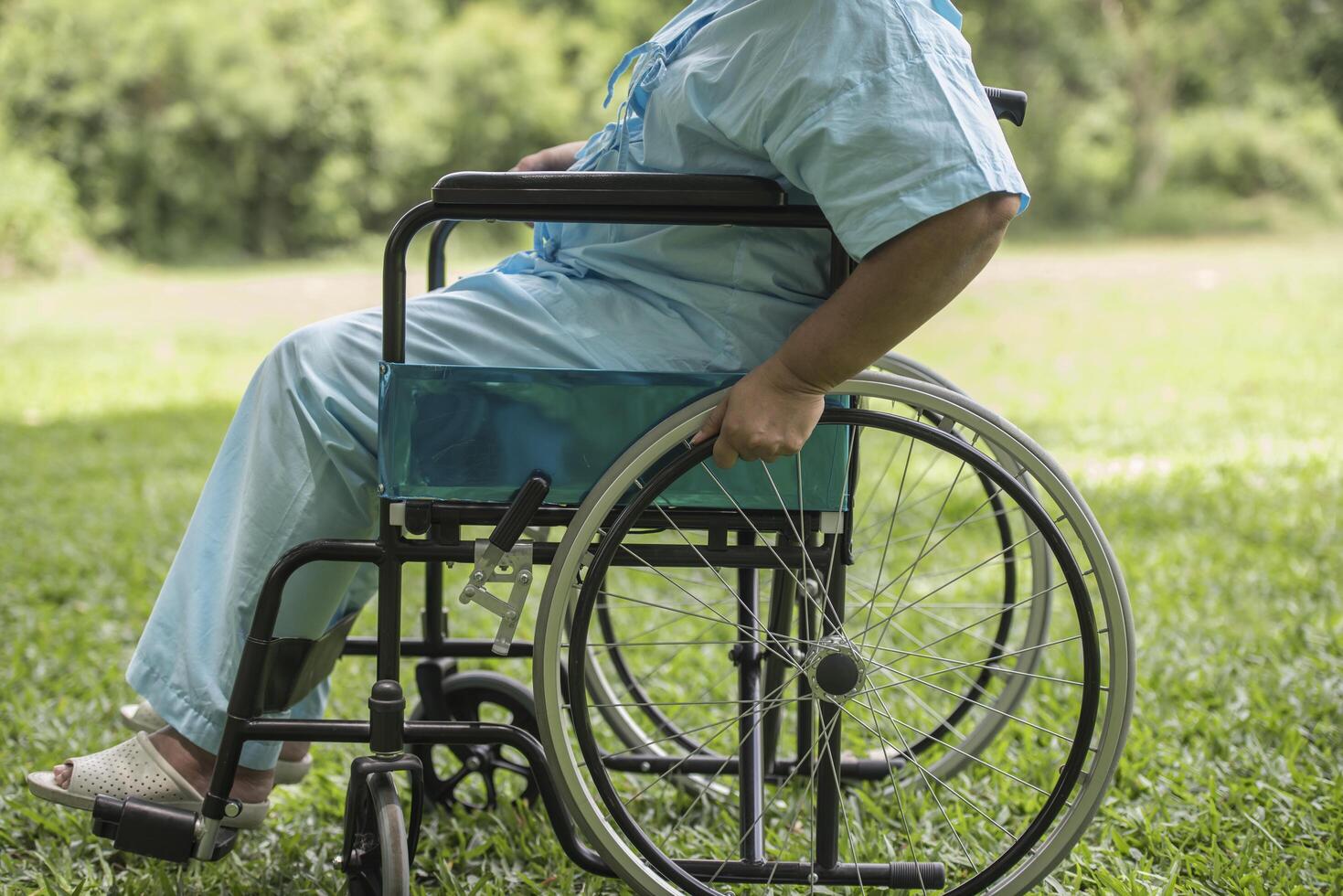 Nahaufnahme einer einsamen älteren Frau, die im Rollstuhl im Garten sitzt foto