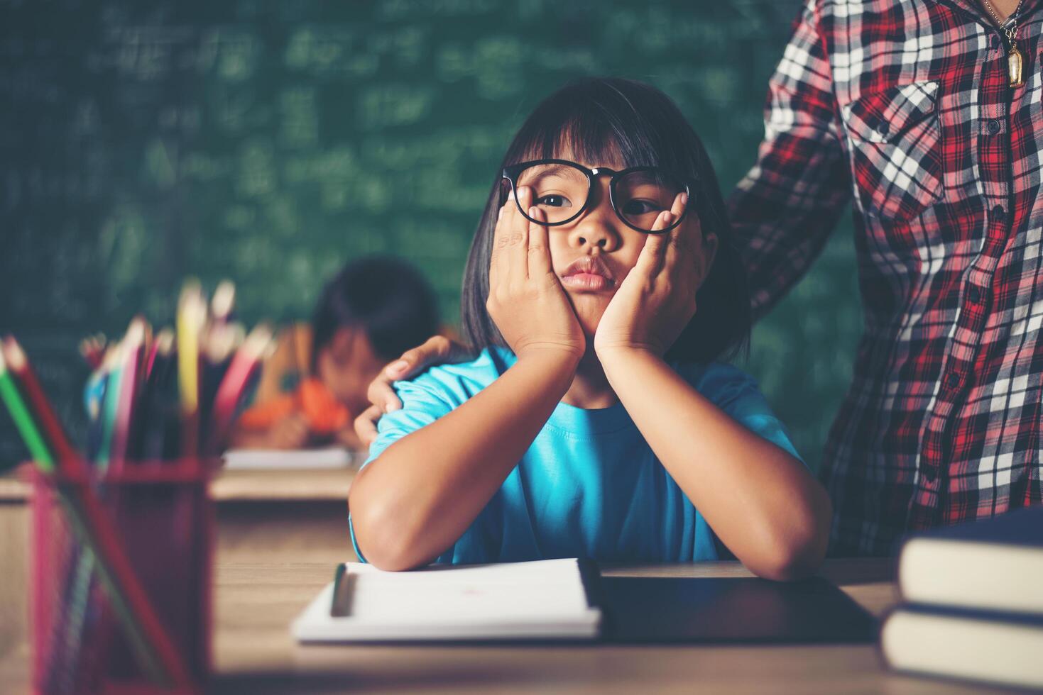 nachdenkliches kleines Mädchen mit Buch in der Nähe einer Schulbehörde foto