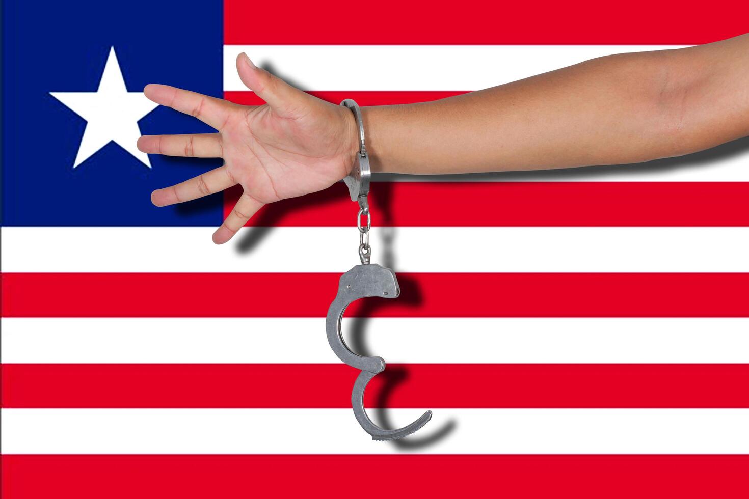 Handschellen mit Hand auf Liberia-Flagge foto